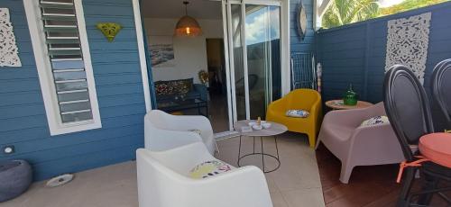 a patio with white chairs and a blue wall at Gîtes Capra Pomme Surette piscine et spa in Bouillante