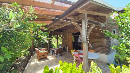 Rivière-PiloteにあるLes chalets Colibris - Anse Figuierの木製の屋根の下にテーブルと椅子付きのパティオ