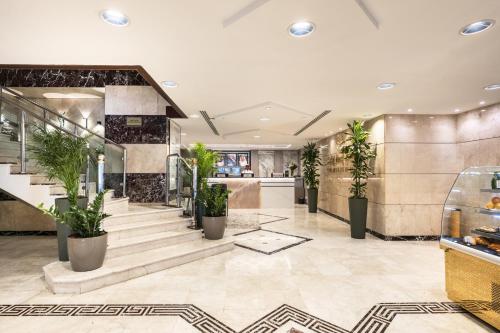 a lobby with a staircase and potted plants at Emaar Elite Al Madina Hotel in Al Madinah