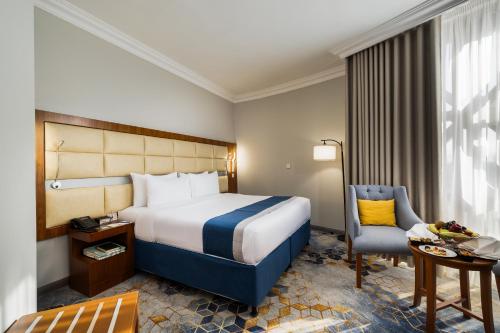 a hotel room with a bed and a desk and a chair at Emaar Elite Al Madina Hotel in Al Madinah