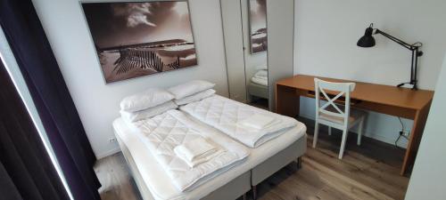 una camera da letto con scrivania e un letto con lenzuola bianche di Koselig leilighet i Mandal a Mandal
