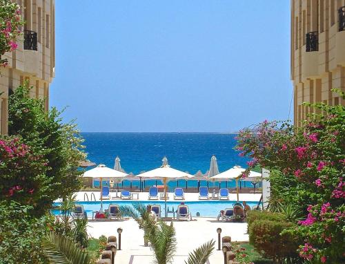 a pool with umbrellas and the ocean in the background at One bedroom apartment A 401 by Peaks Palm Beach Piazza Sahl Hasheesh in Banī Ghālib