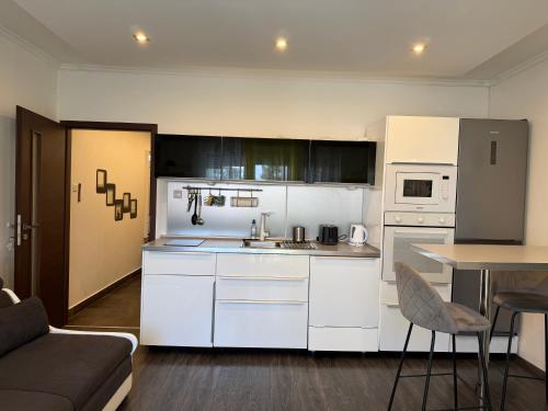a kitchen with white cabinets and a table and a couch at Jégmadár Apartman in Gyula