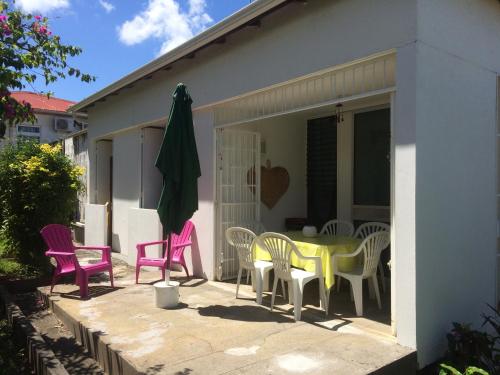 a patio with chairs and a table and a umbrella at Maison Petit Paradis in Basse-Terre