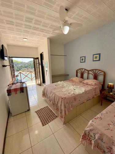 a bedroom with two beds and a balcony at Pousada Costa dos Corais in Mangaratiba