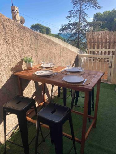 un tavolo in legno con sedie e piatti di Les Alizes Apartment Beachfront a Carry-le-Rouet