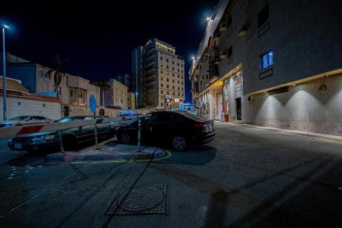 two cars parked on a street at night at زهرة الميناء للشقق المخدومة in Jeddah