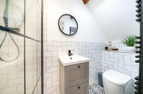 a bathroom with a toilet and a sink and a mirror at School Cottage conversion in Grove Park