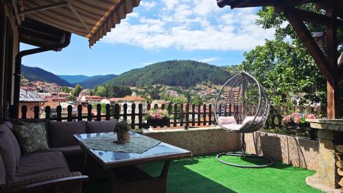 a patio with a table and a chair on a green lawn at Guest House Chepelare in Chepelare