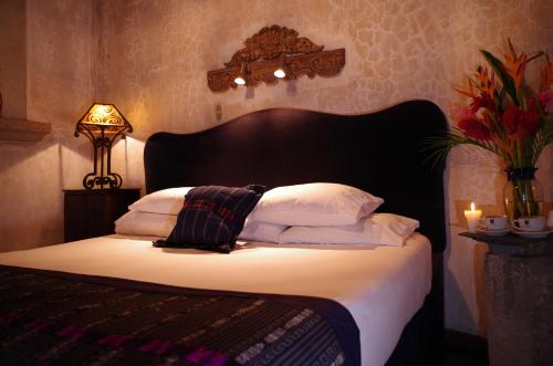a bed with a black headboard and white pillows at Meson Panza Verde in Antigua Guatemala