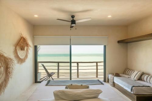 a living room with a ceiling fan and a view of the ocean at AWA Holbox Hotel Boutique - Beach Front in Holbox Island