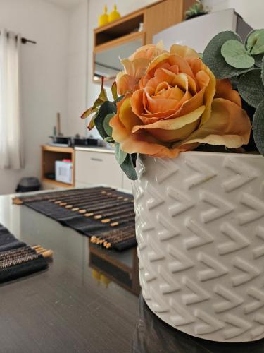 a white vase with a flower in it on a table at Ótimo Apartamento in São José