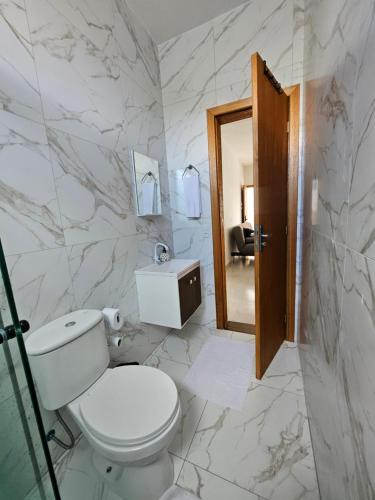 a white bathroom with a toilet and a sink at Ótimo Apartamento in São José