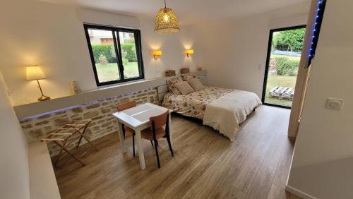 a bedroom with a bed and a table and chairs at Chambres d'hôtes - Studio La Pause Cadurcienne in Cahors