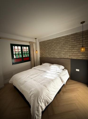 a large white bed in a bedroom with a brick wall at Alma House in Monguí