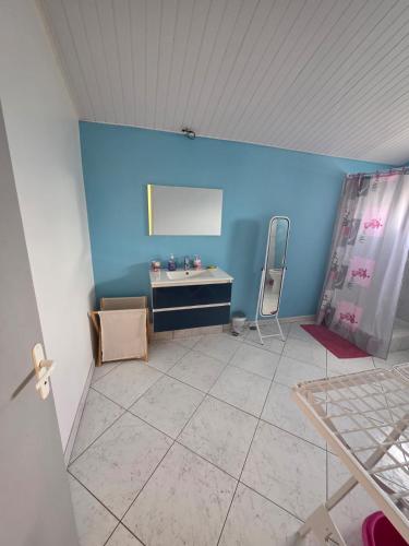 a room with a blue wall and a table and chairs at Chez Josie et Julien in Sainte-Rose