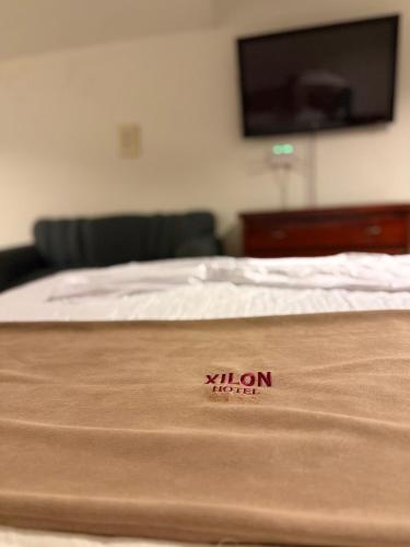 a bed with a tan mattress with a television on the wall at Hotel Xilon Resort Melgar in Melgar