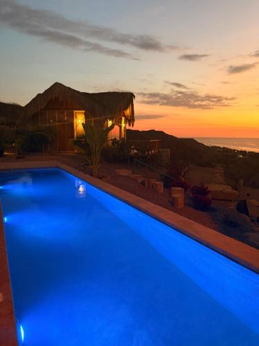 a blue swimming pool in front of a house with the sunset at La Cabaña de Iza in Canoas