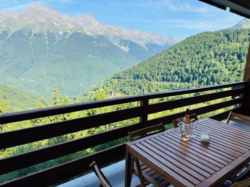 a wooden table with a bottle of wine sitting on a balcony at Apartment l’Alpette Oz en Oisans in Oz