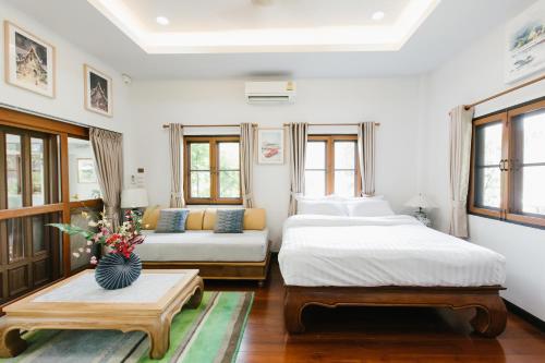 a bedroom with two beds and a couch at Whisper Oasis - Award-Winning Private Jacuzzi Pool Villa - 3BR, Daily Service in Chiang Mai