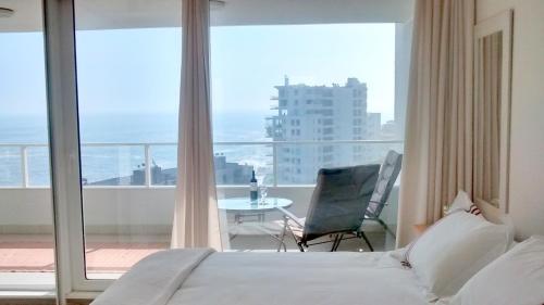 a bedroom with a bed and a balcony with a table at Pacific Blue in Concón