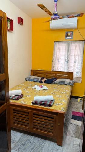 a bed in a room with a yellow wall at Room 3 in Orange Homestay in Thanjāvūr