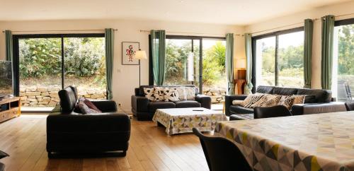 a living room with furniture and large windows at Maison de Saint-Jean in Fouesnant