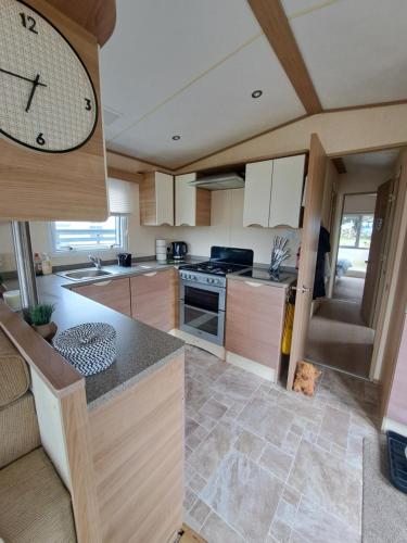 a kitchen with a large clock on the wall at Three lochs holiday park Loch view 123 in Balminnoch