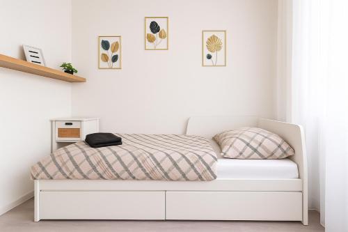 a white bed in a white room with a bed frame at Solis Residence in Hajdúszoboszló