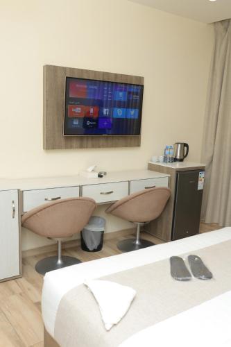 a room with two chairs and a tv on a wall at Sky Hotel in Aqaba