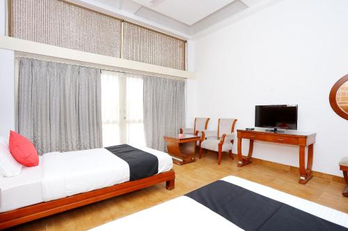 a bedroom with a bed and a desk and a television at Super Townhouse Island Inn in Cochin