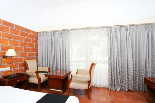 a hotel room with a bed and chairs and a window at Super Townhouse Island Inn in Cochin