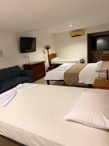 a room with two beds and a couch and a tv at Hotel Xilon Resort Melgar in Melgar