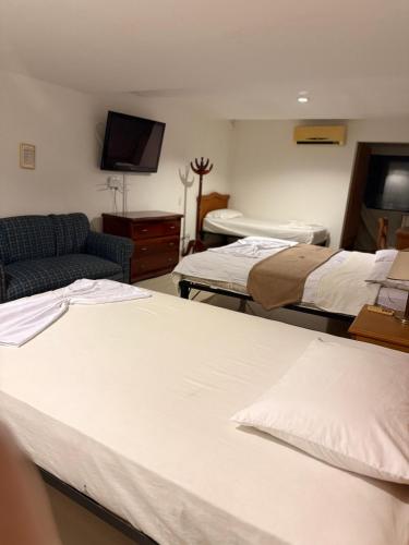 a room with two beds and a couch and a tv at Hotel Xilon Resort Melgar in Melgar