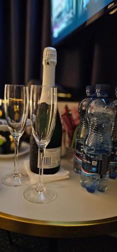 two wine glasses on a table with a bottle of wine at ZAJAZD ALBATROS Rzeszów SPA in Rzeszów