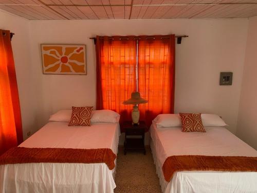 two beds in a room with orange curtains at Tangerine Nest in Port Antonio
