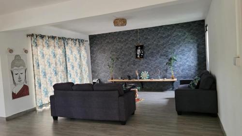 a living room with two couches and a brick wall at Getaway to Mauritius - Évasion à Île Maurice in Eau Bleue