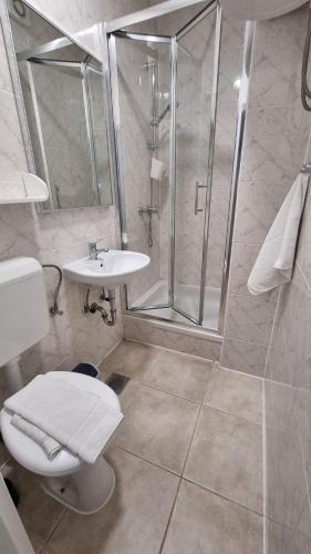 Un baño con ducha, inodoro y lavabo. en Apartments Ostrea - Mimoza, en Novalja