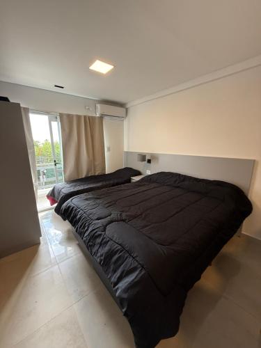 a large black bed in a room with a window at MonoambienteXdia in Villa Dolores