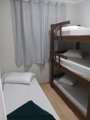 a room with two bunk beds and a window at Apartamento 222 Pé na Praça 1 vaga Garagem 8 hóspedes in Poços de Caldas