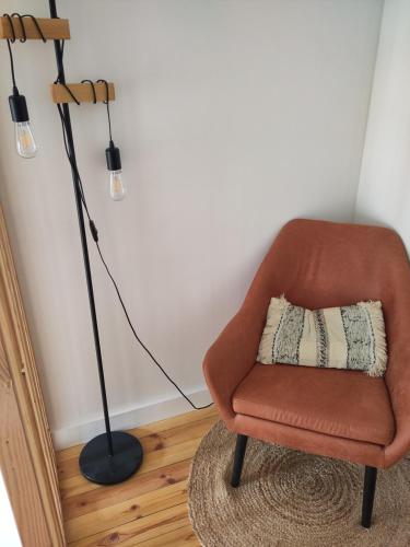 a lamp and a chair with a pillow in a room at Les Trois-Escabelles in Dinant