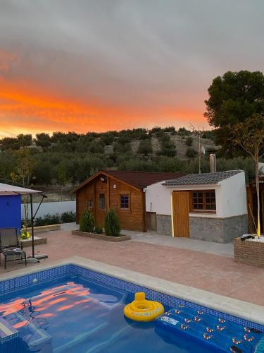 a house with a swimming pool with a sunset in the background at Casa Tita Mari in Jaén