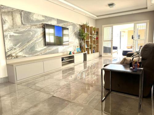 ein Wohnzimmer mit einem Fernseher an der Wand in der Unterkunft Casa dos sonhos na Zona Sul in Ribeirão Preto