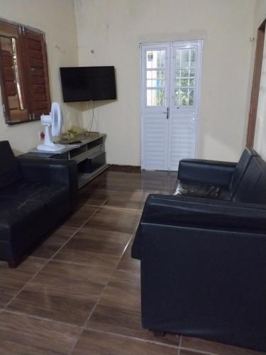 a living room with two black couches and a television at ChacaraSophya in Aquiraz