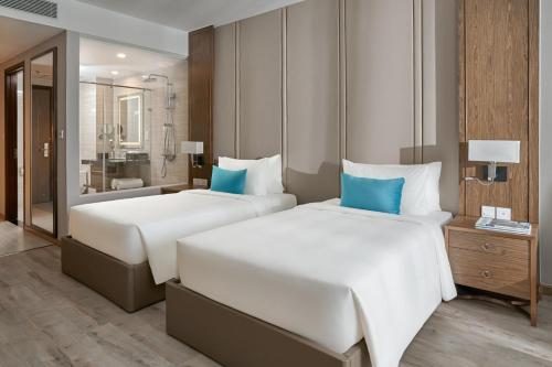 two beds in a hotel room with a bathroom at Tropical Ocean Escape Nha Trang in Nha Trang