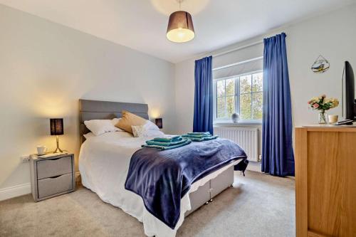 a bedroom with a bed with blue curtains and a window at 3 Fore Street Mews in Framlingham