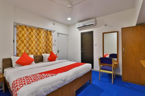 a bedroom with a large bed and a desk and chair at Hotel O Milan Party Hall in Vadodara