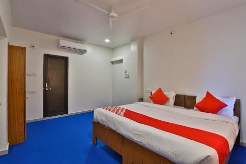 a bedroom with a large bed with red pillows at Hotel O Milan Party Hall in Vadodara