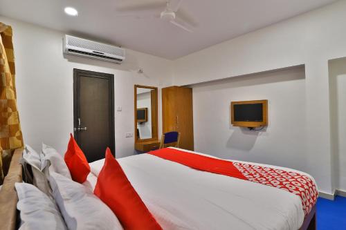 a bedroom with a bed with red pillows and a tv at Hotel O Milan Party Hall in Vadodara