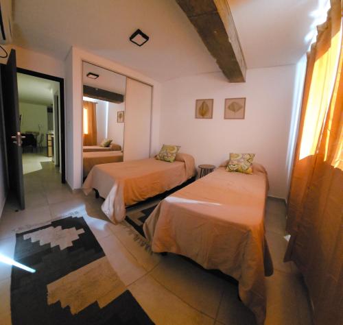 a room with two beds and a living room at DG Rosa María in Santiago del Estero